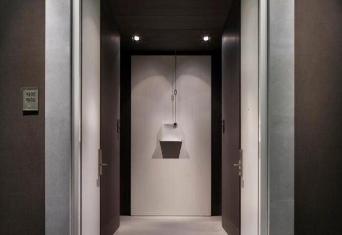 Hallway view at Park Hyatt Shanghai, a gay-friendly hotel. Modern design with open doors, dark wood accents, and unique lighting fixture.