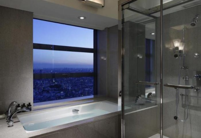 Park Hyatt Tokyo gay-friendly hotel bathroom. Bathtub with Tokyo skyline view. Glass shower. Pet-friendly hotel.
