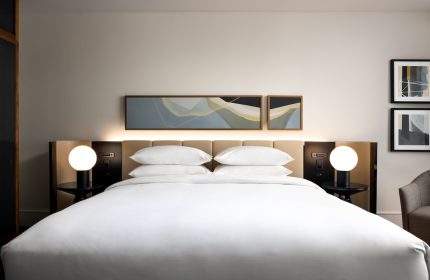 Park Hyatt Toronto gay-friendly hotel room. Modern decor, white linens, and bedside lamps create a welcoming ambiance. Luxury travel.