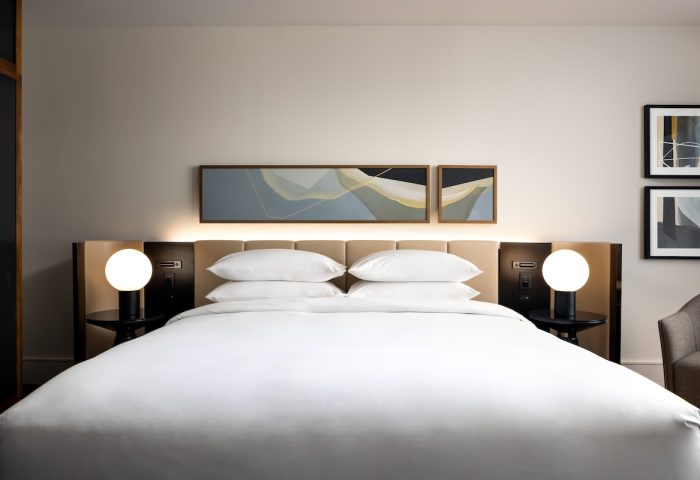 Park Hyatt Toronto gay-friendly hotel room. Modern decor, white linens, and bedside lamps create a welcoming ambiance. Luxury travel.