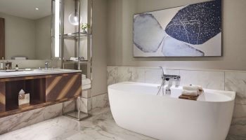 Park Hyatt Toronto bathroom. Modern design with a white tub, marble floor, and abstract art. Gay-friendly hotel for gay men travel advice.