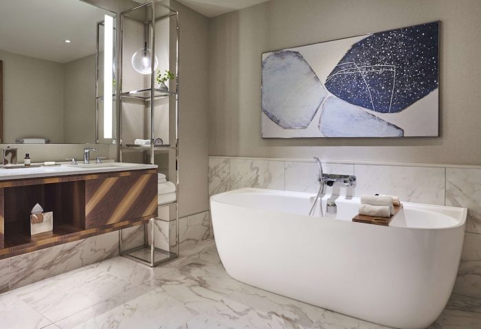 Park Hyatt Toronto bathroom. Modern design with a white tub, marble floor, and abstract art. Gay-friendly hotel for gay men travel advice.