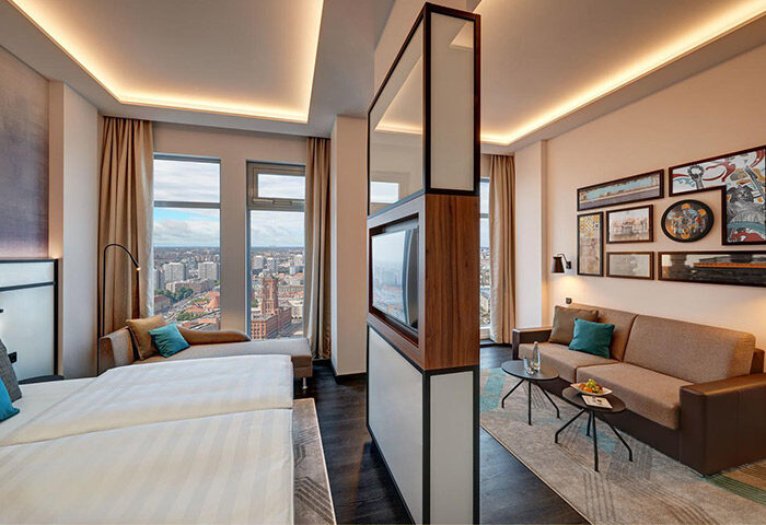 Park Inn by Radisson Berlin Alexanderplatz room. Gay-friendly hotel with city view, bed, sofa, and modern decor. Ideal for gay travelers.