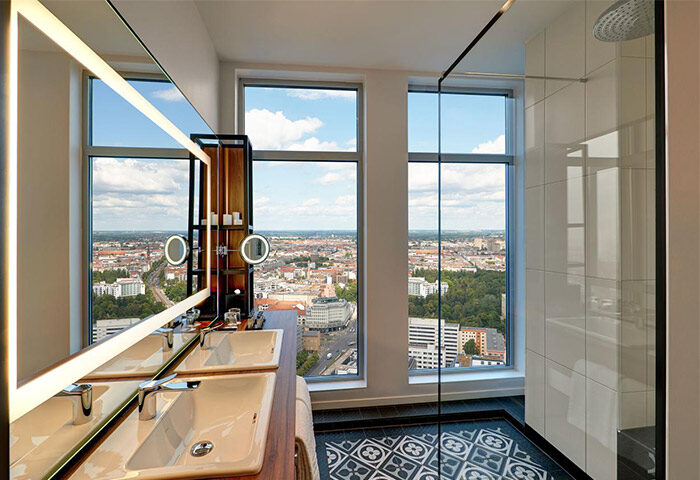 Bathroom with Berlin view at Park Inn by Radisson Alexanderplatz, a gay-friendly hotel. Double sinks, shower, and city skyline.
