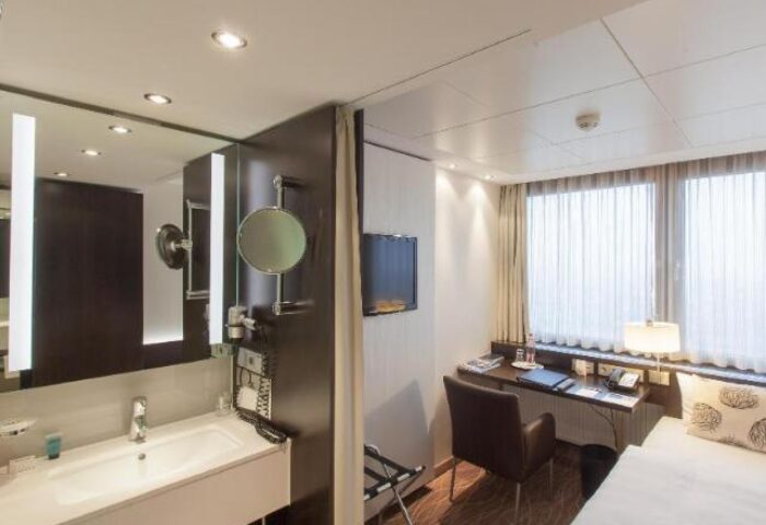 Park Inn by Radisson Berlin Alexanderplatz room. Modern bathroom with sink, mirror, and desk area. Gay-friendly hotel in Berlin.