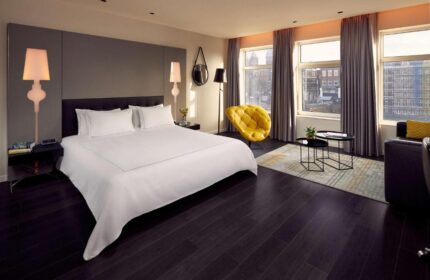 Park Plaza Victoria Amsterdam Hotel room. Modern design, city view, yellow chair. Gay-friendly hotel for gay men travel in Amsterdam.