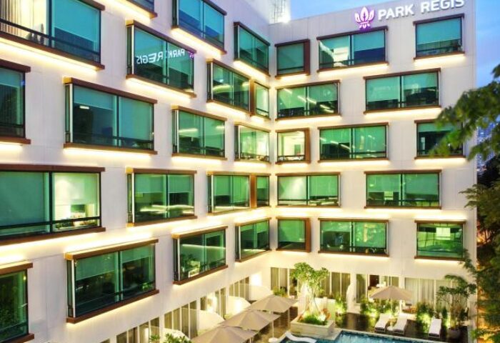 Park Regis Singapore facade. Gay-friendly hotel with pool, lounge chairs, and umbrellas. Modern architecture, ideal for gay travelers.