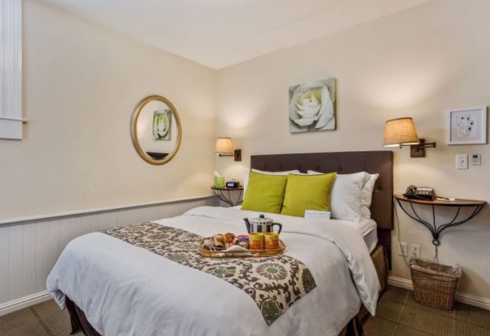 Parker Guest House room. Gay-friendly hotel with bed, breakfast tray, green pillows, & wall art. Ideal for gay men travel.