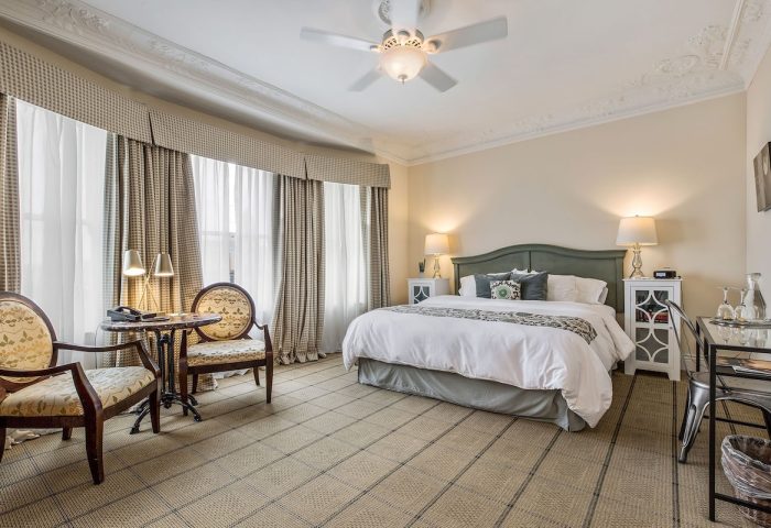 Gay-friendly hotel Parker Guest House room. Bedroom with bed, chairs, table, lamps, and ceiling fan. Travel advice for gay men.