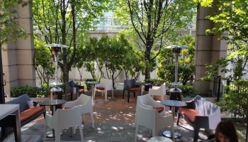 Parker Hotel Vancouver patio. Gay-friendly hotel outdoor seating area with modern chairs, tables, heaters, and lush greenery.