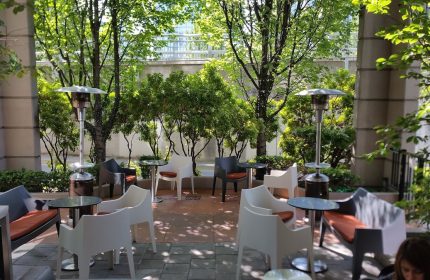 Parker Hotel Vancouver patio. Gay-friendly hotel outdoor seating area with modern chairs, tables, heaters, and lush greenery.
