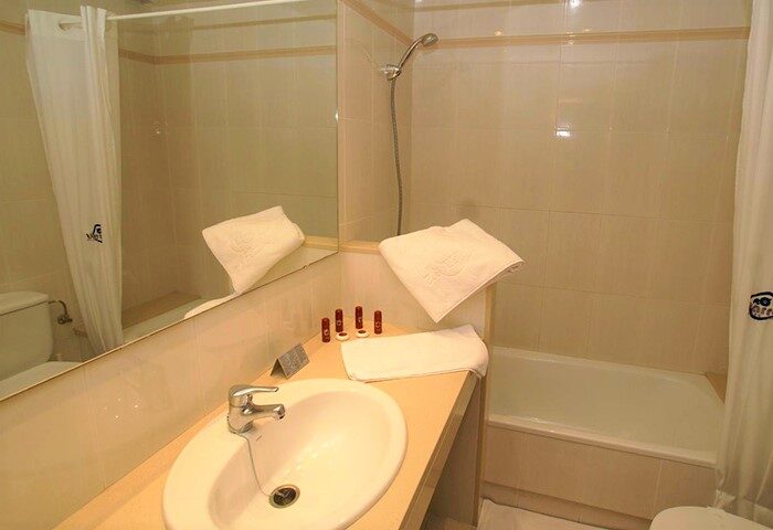 Bathroom at Gay-Friendly Parrots Sitges Hotel. Features sink, mirror, shower, and bathtub. Ideal for gay men's travel in Sitges, Spain.