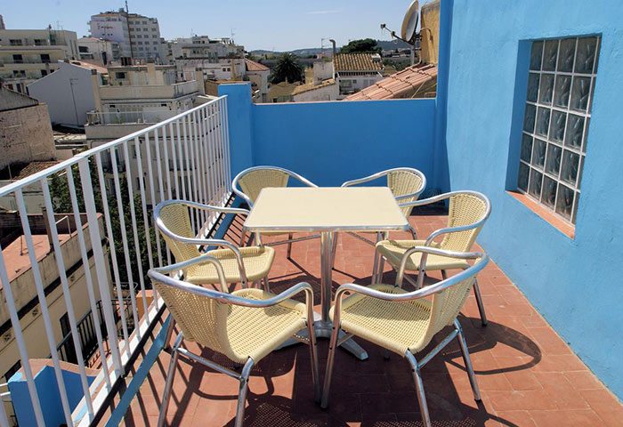 Rooftop terrace at Gay-Friendly Parrots Sitges Hotel. Table and chairs offer a relaxing space with city views. Ideal for gay travel.