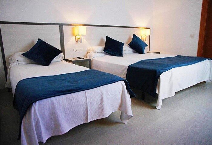 Room at the Gay-Friendly Parrots Sitges Hotel. Two beds with blue accents, a comfortable stay for gay travelers in Sitges.