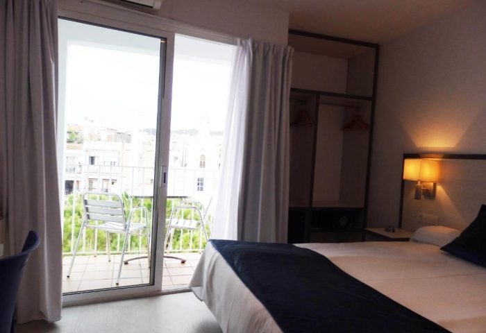 Parrots Sitges Hotel room with balcony. Gay-friendly hotel bedroom with bed, closet, and chairs on the balcony. Gay travel in Sitges, Spain.