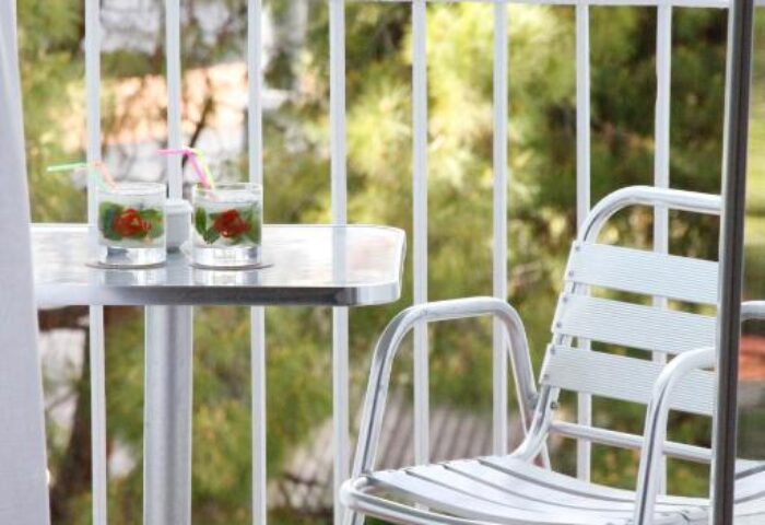 Balcony view at Parrots Sitges Hotel, a gay-friendly hotel. Drinks on a table with a chair. Enjoy your stay at this gay hotel in Sitges.