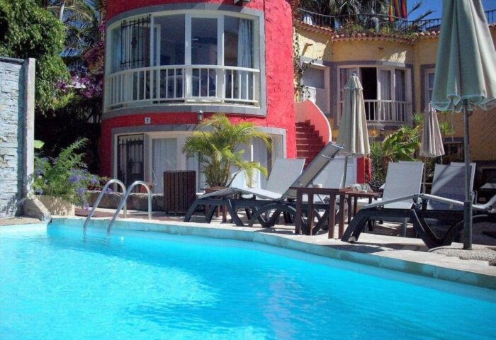 Pasion Tropical Gay Only Resort pool view. Gay-friendly hotel with colorful architecture, sun loungers, and a refreshing pool for gay travelers.
