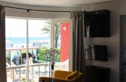 Pasion Tropical Gay Only Resort suite interior. View of balcony, ocean, yellow chairs, and table. Gay-friendly hotel room.