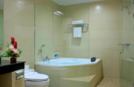Bathroom at Gay-Friendly Pelangi Bali Hotel & Spa. Bathtub, toilet, and shower behind glass. Flowers add a nice touch to this Bali hotel.