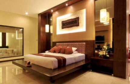 Pelangi Bali Hotel & Spa room. Gay-friendly travel lodging with a king bed on a wooden platform, warm lighting, and modern decor. Bali hotel room.