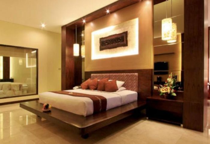 Pelangi Bali Hotel & Spa room. Gay-friendly travel lodging with a king bed on a wooden platform, warm lighting, and modern decor. Bali hotel room.