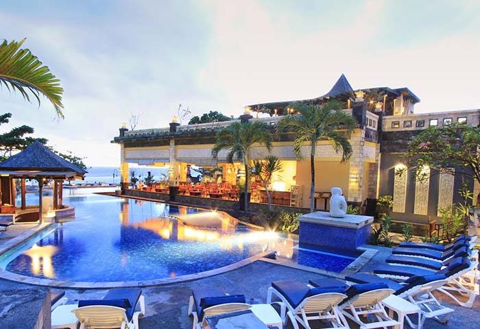Pelangi Bali Hotel & Spa pool area. Gay-friendly hotel with poolside lounge chairs, restaurant, and ocean view. Bali travel for gay men.