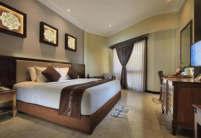 Pelangi Bali Hotel & Spa room. Gay-friendly hotel bedroom with king-size bed, desk, and Balinese art. Relaxing vacation for gay men.