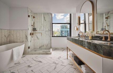 Pendry Chicago gay-friendly hotel bathroom. Marble shower, tub, and double vanity. City view. Luxury design for gay men travel.