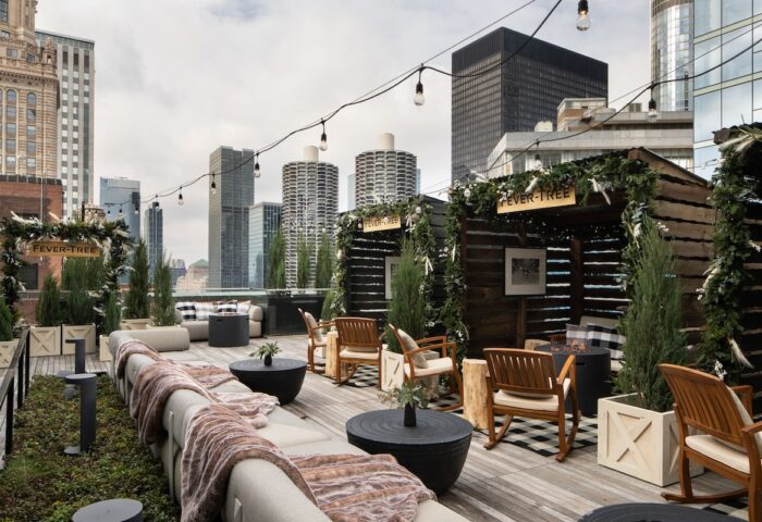 Pendry Chicago gay-friendly hotel rooftop bar. Outdoor lounge with city views, string lights, wooden chairs, and Fever-Tree signage.