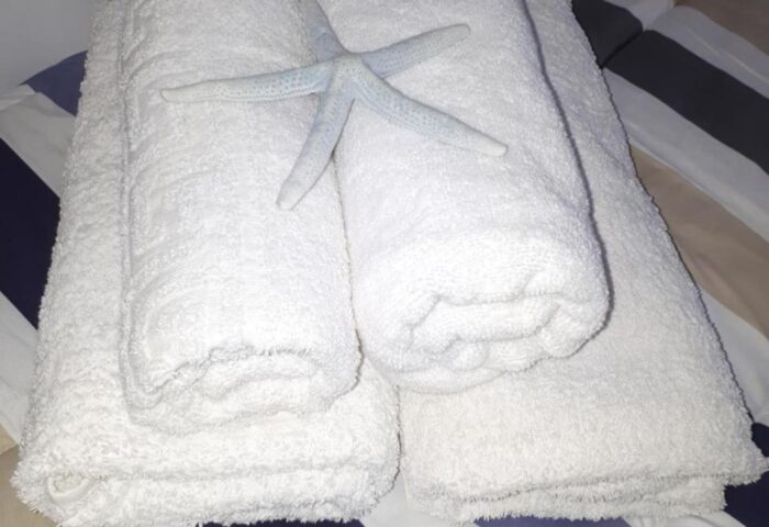 Pension Ageliki Kalogera: White towels and starfish on a striped bed. Gay-friendly hotel room detail, welcoming guests.