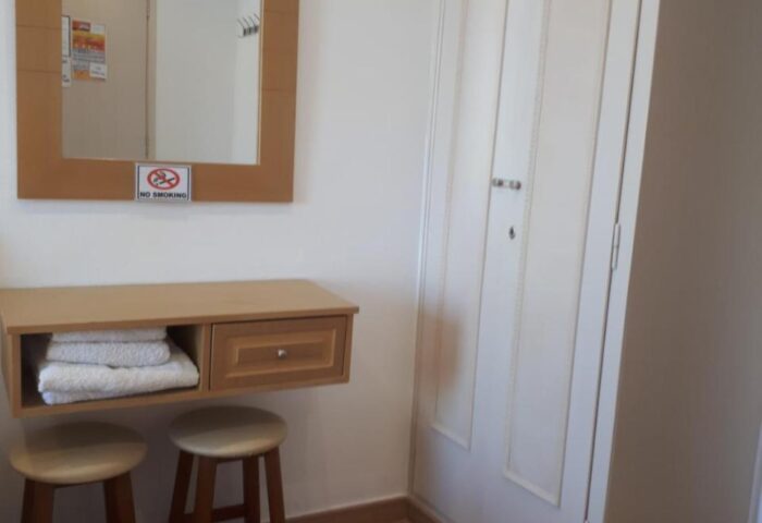 Pension Ageliki Kalogera room detail. Mirror, shelf with towels, stools, and wardrobe. Gay-friendly hotel interior.