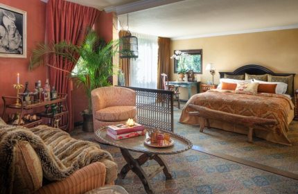 Petit Ermitage Hotel adults-only suite. Gay-friendly hotel room with eclectic decor, seating area, bar cart, and king bed. Luxury gay travel.