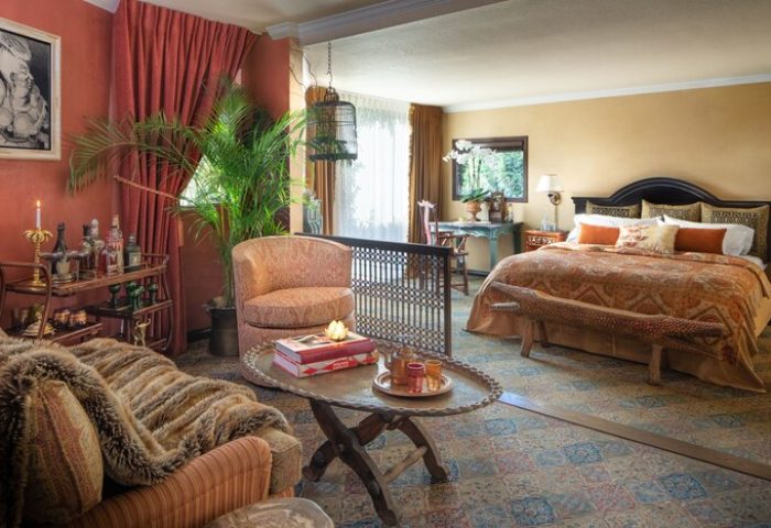 Petit Ermitage Hotel adults-only suite. Gay-friendly hotel room with eclectic decor, seating area, bar cart, and king bed. Luxury gay travel.