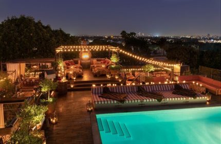 Petit Ermitage Hotel adults-only rooftop pool at night. Gay-friendly hotel with city views, string lights, and cozy lounge areas.