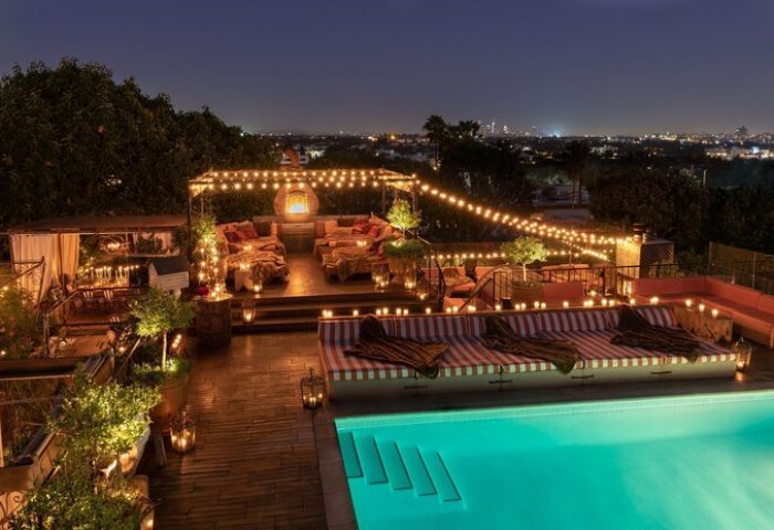 Petit Ermitage Hotel adults-only rooftop pool at night. Gay-friendly hotel with city views, string lights, and cozy lounge areas.