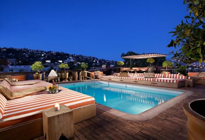 Petit Ermitage Hotel Adults-Only rooftop pool at night. Gay-friendly hotel with striped daybeds and city views. Perfect for gay travel.