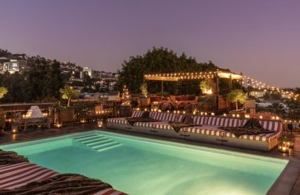 Rooftop pool at Petit Ermitage Hotel, an adults-only, gay-friendly hotel. Night scene with candles, lights, and city views.