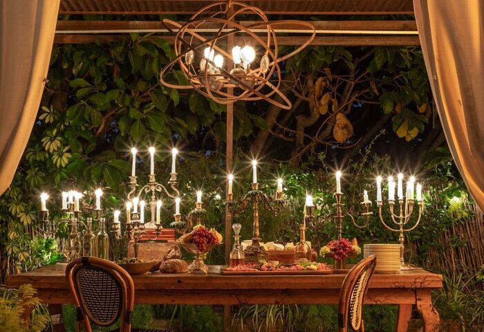 Petit Ermitage Hotel, an adults-only, gay-friendly hotel. Outdoor dining area with a long table set with candles and food. Romantic ambiance.