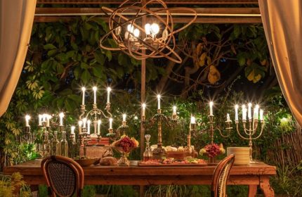 Petit Ermitage Hotel, an adults-only, gay-friendly hotel. Outdoor dining area with a long table set with candles and food. Romantic ambiance.
