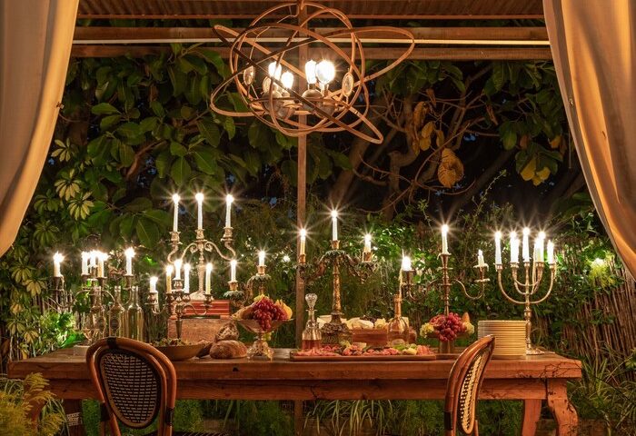 Petit Ermitage Hotel, an adults-only, gay-friendly hotel. Outdoor dining area with a long table set with candles and food. Romantic ambiance.