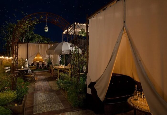 Petit Ermitage Hotel adults-only rooftop garden at night. Romantic gay-friendly hotel dining with tents and cozy seating.