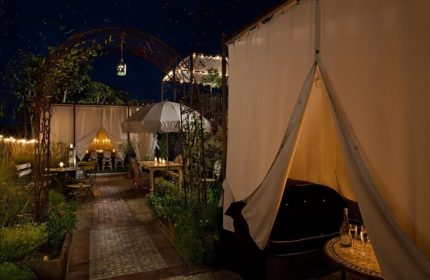 Petit Ermitage Hotel adults-only rooftop garden at night. Romantic gay-friendly hotel dining with tents and cozy seating.