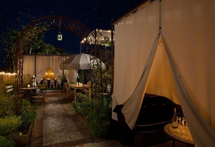 Petit Ermitage Hotel adults-only rooftop garden at night. Romantic gay-friendly hotel dining with tents and cozy seating.