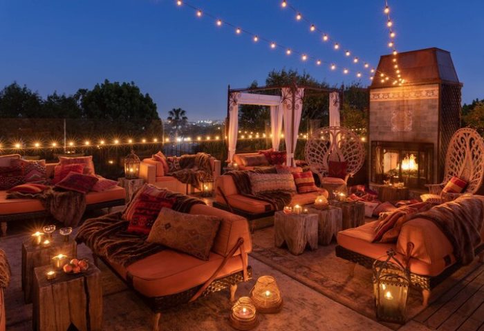 Petit Ermitage Hotel adults-only rooftop terrace at dusk. Cozy seating, fireplace, and string lights create a romantic, gay-friendly ambiance.