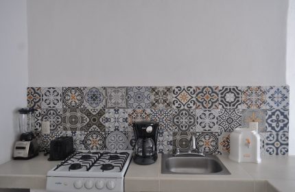 Petit Hotel Pilitas gay-friendly hotel kitchenette. Features stove, sink, coffee maker, blender, toaster, and decorative tile backsplash.