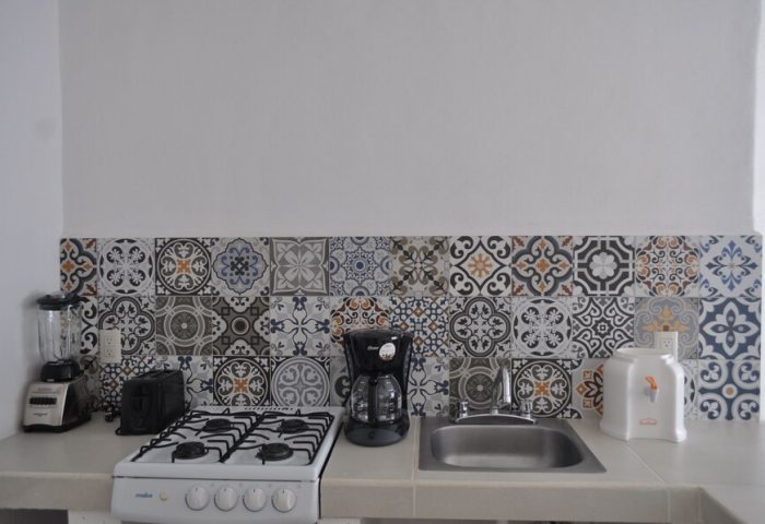 Petit Hotel Pilitas gay-friendly hotel kitchenette. Features stove, sink, coffee maker, blender, toaster, and decorative tile backsplash.
