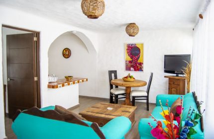 Petit Hotel Pilitas gay-friendly hotel room. Living area with turquoise sofas, wooden table, and decor. Vacation travel for gay men.