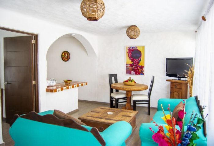 Petit Hotel Pilitas gay-friendly hotel room. Living area with turquoise sofas, wooden table, and decor. Vacation travel for gay men.
