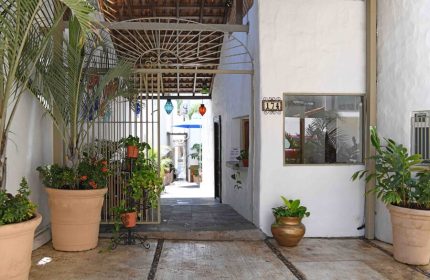Petit Hotel Pilitas entrance. Gay-friendly hotel with plants, open gate, and colorful lanterns. Perfect for gay travel in a relaxed setting.
