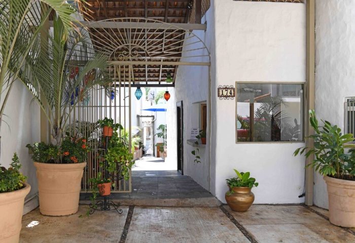 Petit Hotel Pilitas entrance. Gay-friendly hotel with plants, open gate, and colorful lanterns. Perfect for gay travel in a relaxed setting.